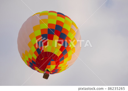 Colorful hot air balloon flying against grey sky at Winter aerostat festival 86235265