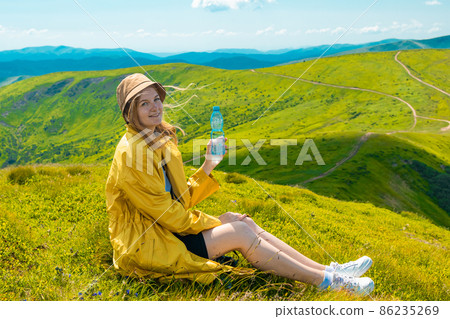 Hiker traveler female holding bottle with fresh water outdoors on the top of the mountain. Drinking water and health Hiker traveler female holding bottle with fresh water outdoors on the top of the mountain. Drinking water and health 86235269