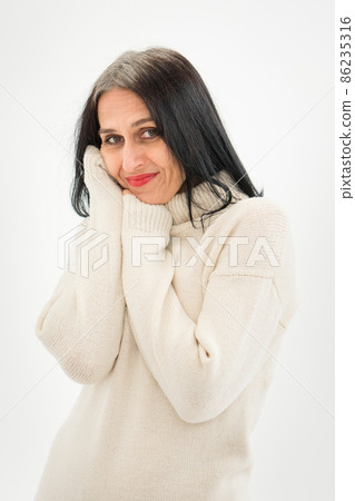 Middle aged woman starting getting grey-haired is posing in studio in sweater on white background, face skin care beauty, middle age skincare cosmetics, cosmetology concept Middle aged woman starting getting grey-haired is posing in studio in sweater on white background, face skin care beauty, middle age skincare cosmetics, cosmetology concept 86235316