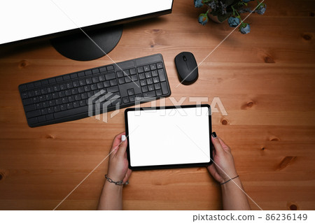 Young woman sitting in front of computer and using digital tablet. 86236149