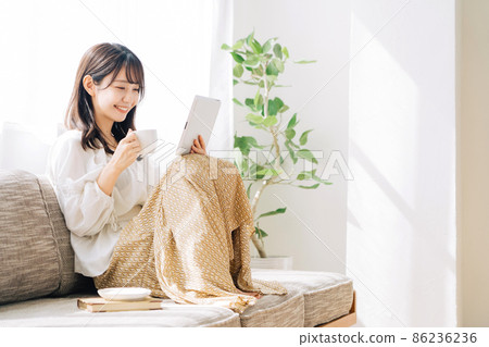 A woman watching a tablet while drinking coffee 86236236