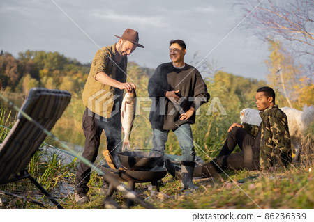 Man putting big fish for cooking Ukha near friends 86236339