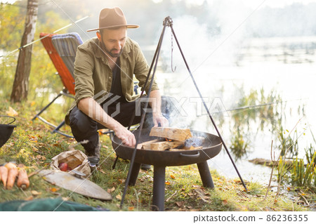 Man making fire in grill for cooking at nature 86236355