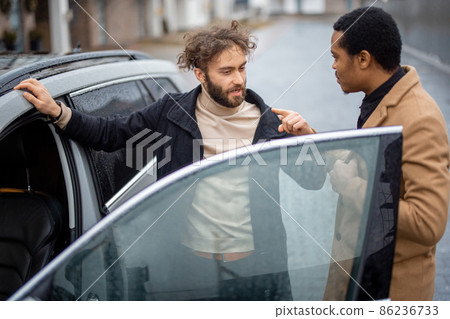 Two men flirting while standing near car on the street 86236733