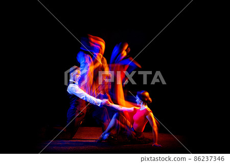 Dynamic portrait of young ballroom dancers dancing Argentine tango isolated on dark background with neon mixed light. Dynamic portrait of young ballroom dancers dancing Argentine tango isolated on dark background with neon mixed light. 86237346