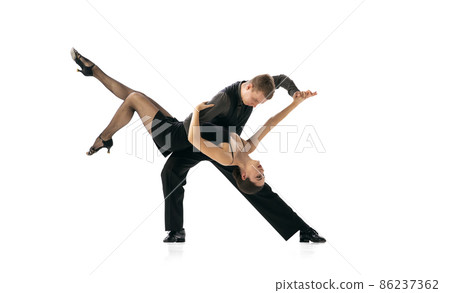Beautiful sportive young man and woman dancing Argentine tango isolated on white studio background. Artists in black stage costumes Beautiful sportive young man and woman dancing Argentine tango isolated on white studio background. Artists in black stage costumes 86237362