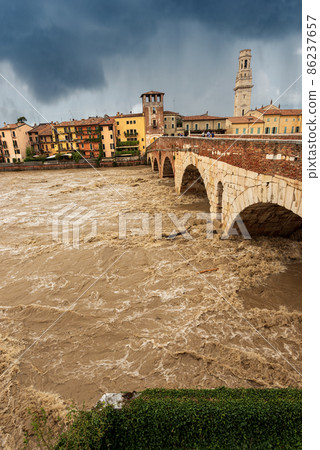 Ponte Pietra - Stone bridge and Adige river in flood in Verona Veneto Italy 86237657