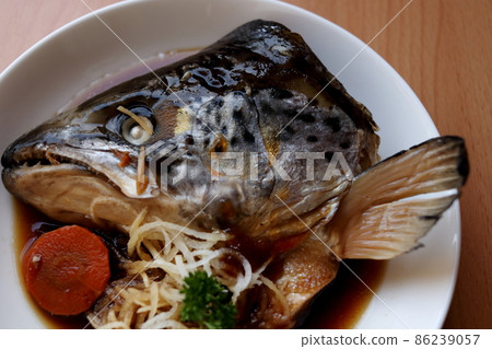 Salmon's head boiled in soy sauce on white dish. 86239057