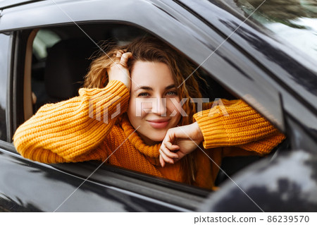 Portrait of young beautiful woman in yellow sweater sitting in the car. Portrait of young beautiful woman in yellow sweater sitting in the car. 86239570