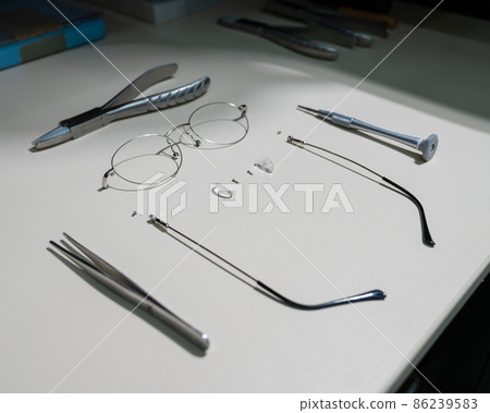 Disassembled glasses frame and tools. Optics work table. 86239583