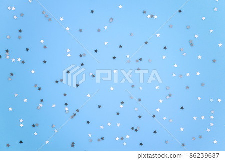 Silver stars glittering confetti on blue background. Trendy festive holiday backdrop. Many star-shaped particles for a postcard, invintation or web banner 86239687