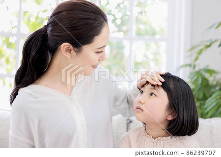 A mother who puts her hand on her child's forehead to check for fever 86239707