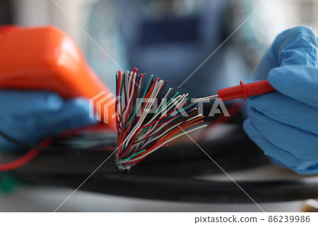 Master repairman testing multicolored wires from cable using tester closeup Master repairman testing multicolored wires from cable using tester closeup 86239986