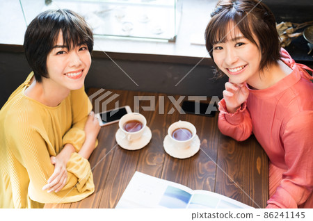 在咖啡廳看小冊子製定旅行計劃的兩個女人拍攝合作“西式糖果店情調” 86241145