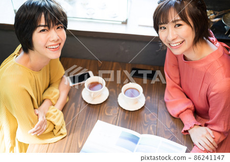 在咖啡廳看小冊子製定旅行計劃的兩個女人拍攝合作“西式糖果店情調” 在咖啡廳看小冊子製定旅行計劃的兩個女人拍攝合作“西式糖果店情調” 86241147