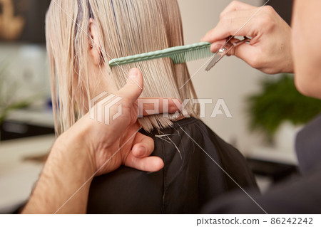 Hairdresser combing and cutting woman hair in beauty salon Hairdresser combing and cutting woman hair in beauty salon 86242242