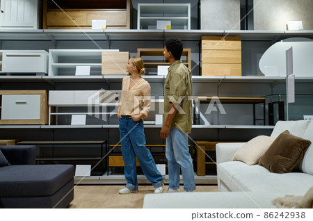 Young multiracial couple considering furniture store assortment Young multiracial couple considering furniture store assortment 86242938