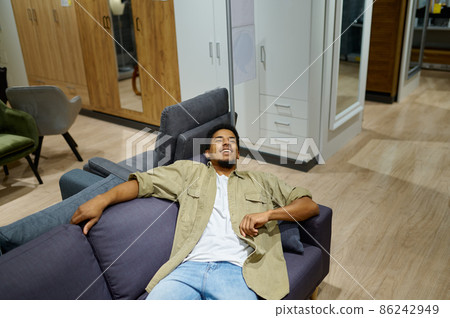 Man on couch in furniture store showroom Man on couch in furniture store showroom 86242949