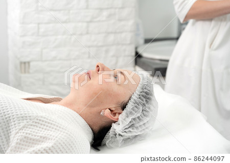 Mature woman receiving facial treatment mask in spa beauty salon. Concept of skin care for older people 86244097