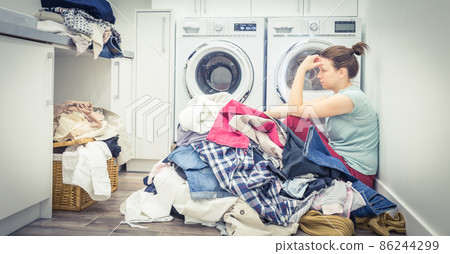 Sad tired Woman in laundry room, blue tone Sad tired Woman in laundry room, blue tone 86244299