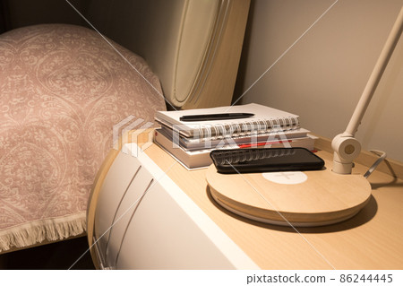 Smartphone in black case charging wireless on bed table 86244445