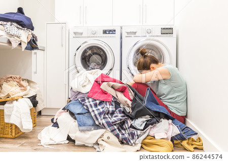 Sad woman sitting in a laundry room Sad woman sitting in a laundry room 86244574