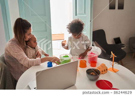 Little boy playing with kinetic sand at home near his mother and brother Little boy playing with kinetic sand at home near his mother and brother 86244629
