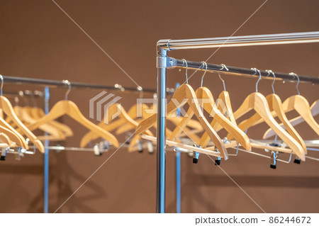 Wooden coat hangers on coat rack with no clothes in cloakroom Wooden coat hangers on coat rack with no clothes in cloakroom 86244672