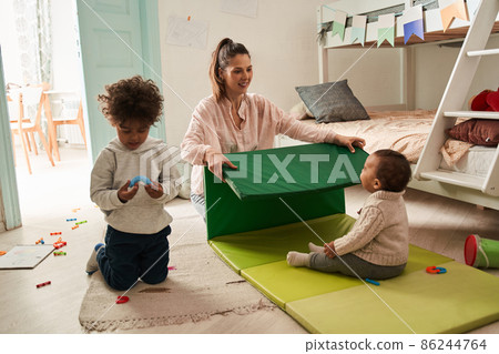Happy woman playing with male kids at the floor at home and laughing while spending great weekend Happy woman playing with male kids at the floor at home and laughing while spending great weekend 86244764