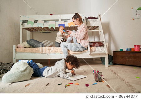 Joyful happy family of single mother and two son sitting together at the bedroom while playing Joyful happy family of single mother and two son sitting together at the bedroom while playing 86244877