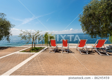 Empty Deck Chairs on a Beautiful Beach on Lake Garda - Veneto Italy 86245459