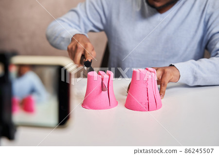 Blogger guy holding knife and preparing destroying pink molds from kinetic sand Blogger guy holding knife and preparing destroying pink molds from kinetic sand 86245507