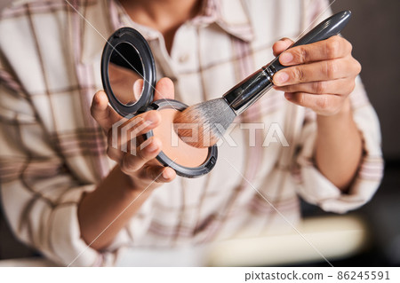Woman picks up blush on the brush while broadcasting make up tutorial 86245591