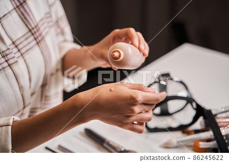 Blogger woman putting drop of her tone cream at hand while broadcasting make up tutorial 86245622