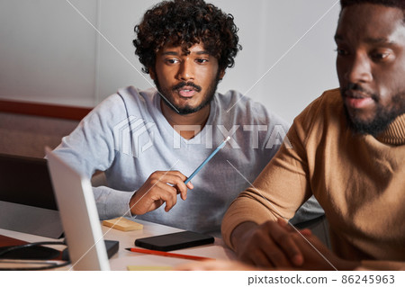 Group of friends using laptop in coworking while discussing their work Group of friends using laptop in coworking while discussing their work 86245963