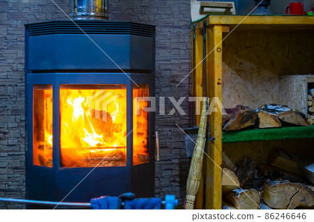 view of a metal furnace with tempered refractory glass, in which a bright flame of fire burns 86246646