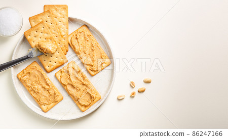 Peanut butter spread on soda crackers on the plate Peanut butter spread on soda crackers on the plate 86247166