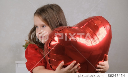 Pretty cute girl holding heart shaped crane balloons on valentines day. 86247454