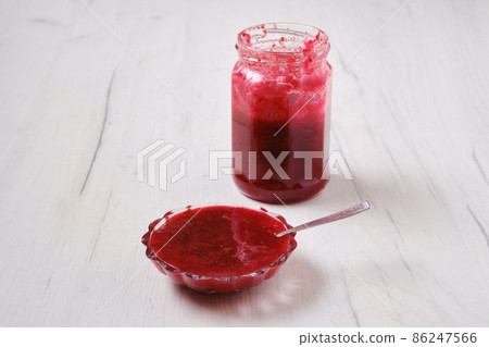 Jar and saucer with cherry jam on white wooden background Jar and saucer with cherry jam on white wooden background 86247566
