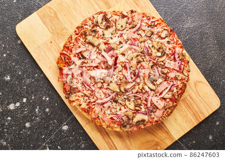 Fast food, Baked frozen pizza with ham, mushrooms and cheese on thick dough. Ready to eat. Fast food, Baked frozen pizza with ham, mushrooms and cheese on thick dough. Ready to eat. 86247603