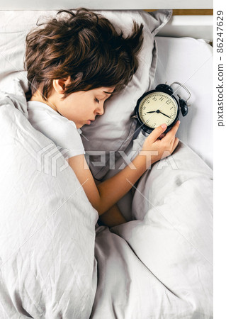 Boy sleeping after turning off his alarm clock 86247629