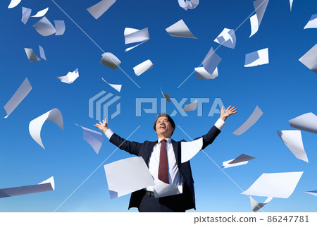 A smiling business person who throws documents toward the blue sky A smiling business person who throws documents toward the blue sky 86247781