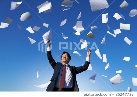 A smiling businessman who throws documents toward the blue sky 86247782