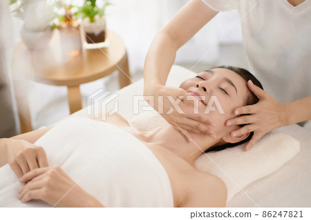 Middle-aged woman receiving a massage at an esthetic salon Middle-aged woman receiving a massage at an esthetic salon 86247821