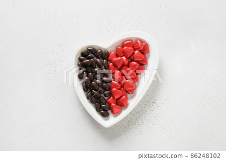 Red chocolate sweets as heart on white background. Valentine's day concept. Red chocolate sweets as heart on white background. Valentine's day concept. 86248102