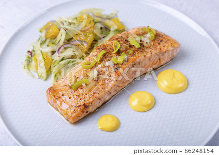 Fried salmon with fennel and orange salad with hollandaise sauce. Garnished with leeks. French dish. Close-up. Fried salmon with fennel and orange salad with hollandaise sauce. Garnished with leeks. French dish. Close-up. 86248154