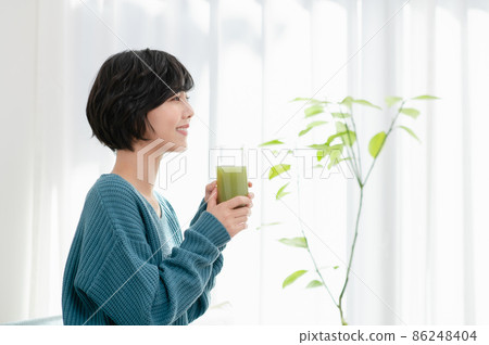 A young woman drinking vegetable juice 86248404