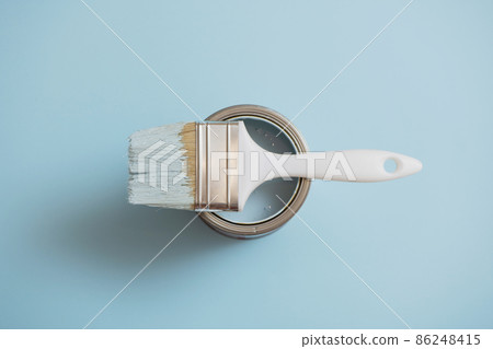 Top view of paint brush lying on open can of blue paint on blue background. Top view of paint brush lying on open can of blue paint on blue background. 86248415