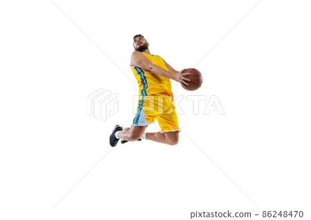 Dynamic portrait of professional basketball player jumping with ball isolated on white studio background. Sport, motion, activity, movement concepts. 86248470