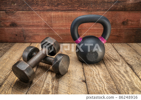 small iron kettlebell and dumbbell on a rustic wood small iron kettlebell and dumbbell on a rustic wood 86248916